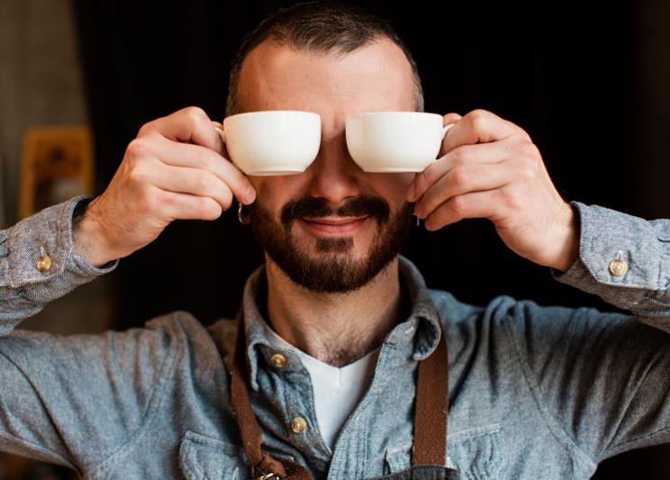 playful man posing with coffee cups