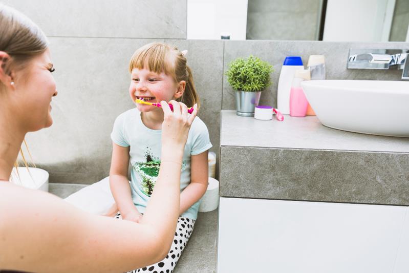 mother brushing teeth of daughter