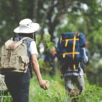 A happy hiker walks through the jungle with a backpack.