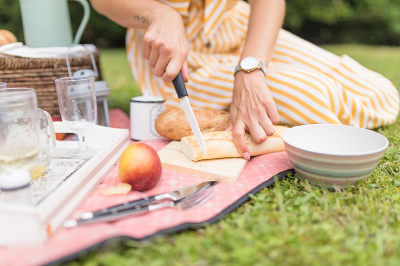 woman cutting bread with knife at picnic