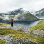 hiker standing beside a lake in the lofoten mountains