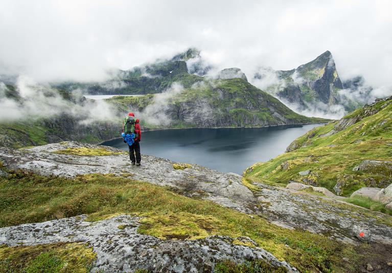 hiker standing beside a lake in the lofoten mountains