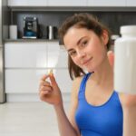 woman fitness instructor showing bottle of vitamins
