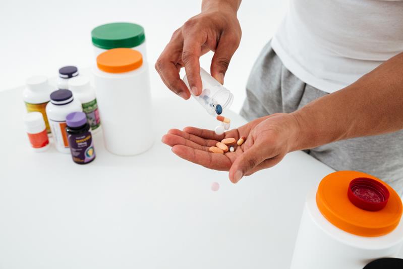 young sportsman holding vitamins and sport pills