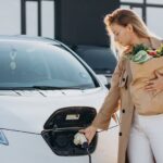 woman with food shopping bags charging electric car