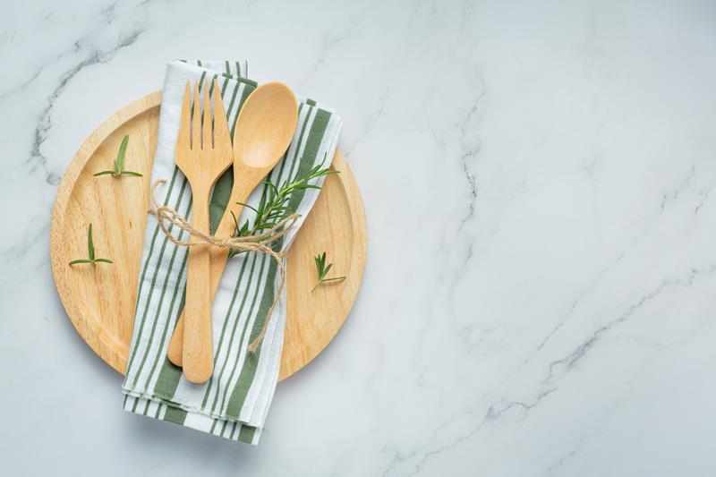 wooden spoon and fork with rosemary plants on wooden plate