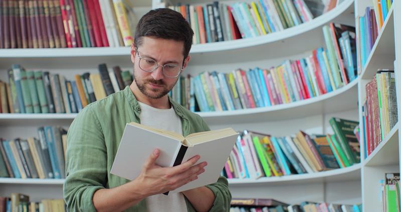 portrait of focused man in-glasses reading book