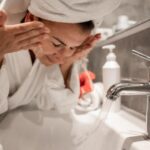 young woman in the bathroom washes her face with tap water