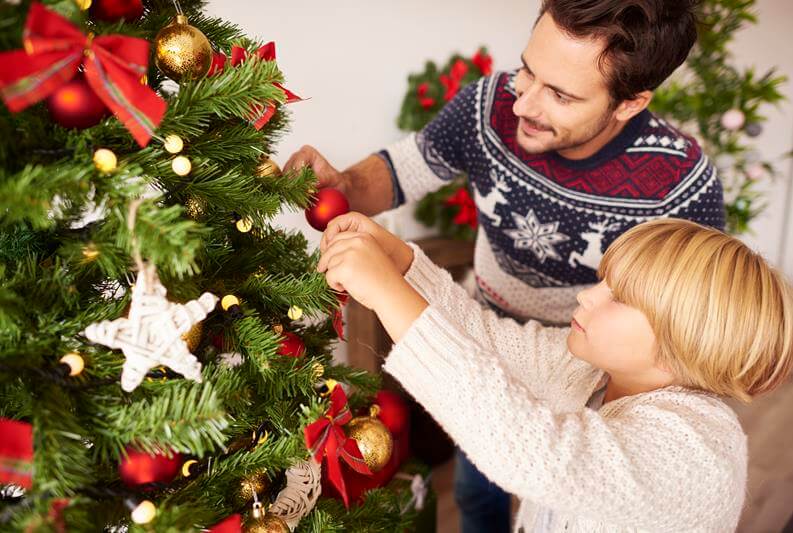 A person decorating an eco-friendly Christmas tree